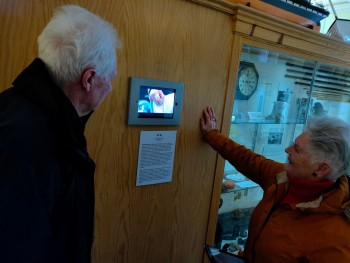 Morag and her husband watching the MAMC film at Stromness Museum in March 2020 A man and woman watching a film on an iPad mounted on a wall