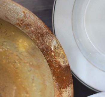 Wash basin salvaged from the German Fleet, Stromness Museum. Image: Mary Grieve A close up image of the edges or rims of two objects, One the left if the rim of a wash basin, the glaze is cracked and worn . To the right is the rum of a white dinner plate with black edged line.
