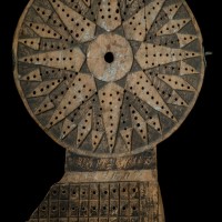 A dark wooden traverse board used in navigation.  The holes in the board are used for pegs.