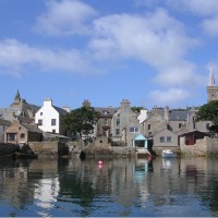 Stromness from the sea showing the houses huddled together along the harbour. Image credit: Creative commons